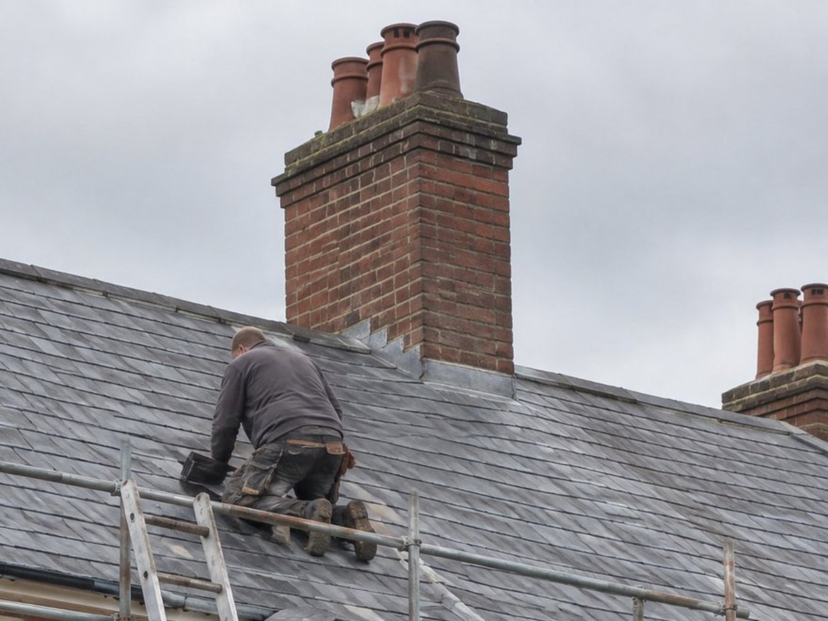 Roofer working beside a brick chimney stack